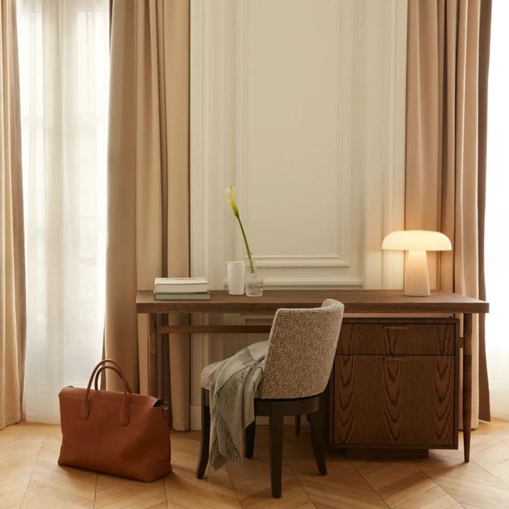 Elegant luxury hotel room with cream-colored decor, king bed, tall windows with sheer curtains, ornate wall moldings, and chic lighting fixtures