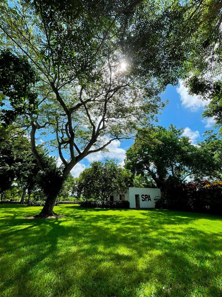 Elegant colonial-style villa with lush tropical gardens, white exterior, vibrant bougainvillea, and traditional Mexican architectural details at luxury boutique resort