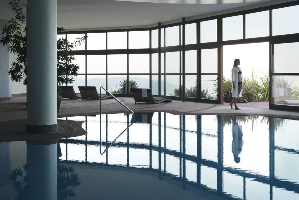 Infinity pool overlooking Lake Garda and mountains, modern stone resort with terraced gardens and panoramic lake-view suites