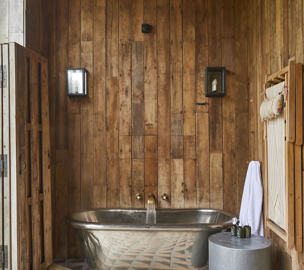 Luxurious forest cabin interior at Lime Wood, featuring rustic wooden walls, plush king-sized bed, and elegant forest-inspired decor with soft natural lighting