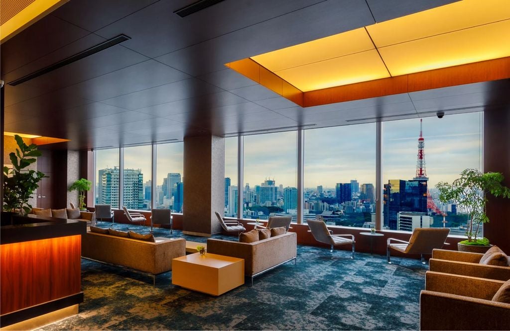 Modern luxury hotel exterior in Japan with sleek glass facade, dramatic night lighting, and zen-inspired landscaping featuring stone gardens