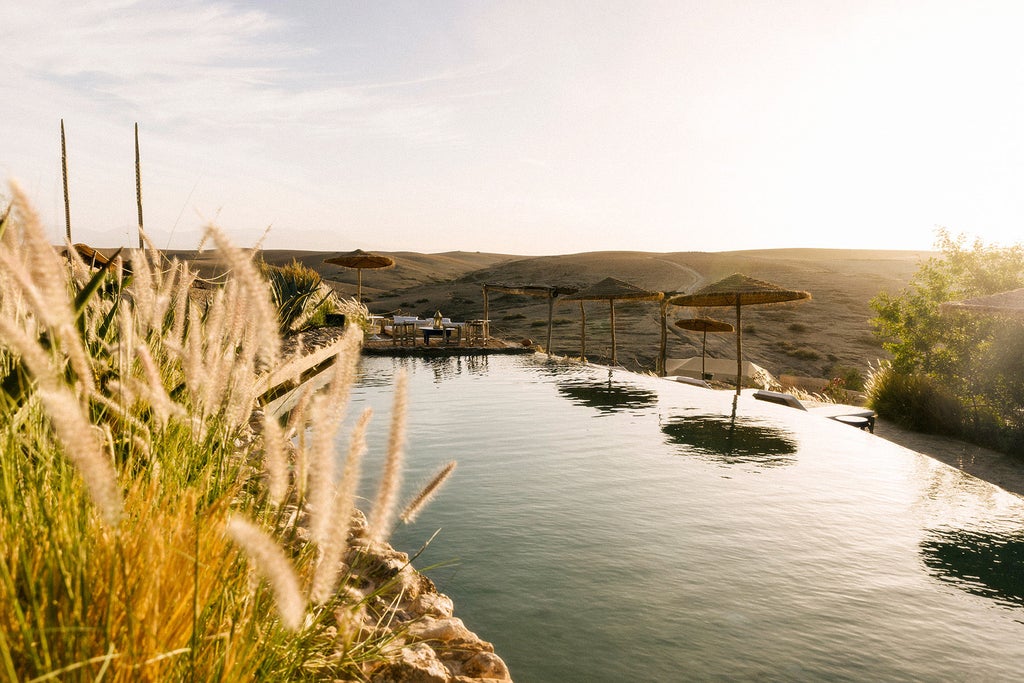 Luxurious desert tent lodging with panoramic Atlas Mountains views, featuring modern canvas dome, private terrace and desert landscaping