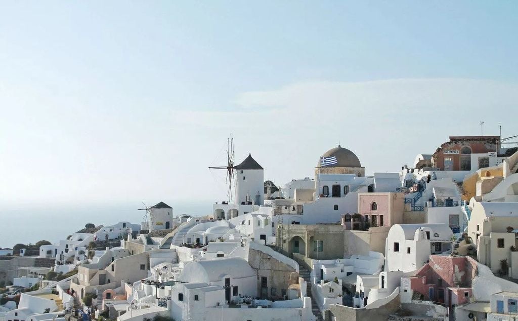 Elegant infinity pool overlooking Santorini's caldera at sunset, featuring white terraces and traditional Cycladic architecture