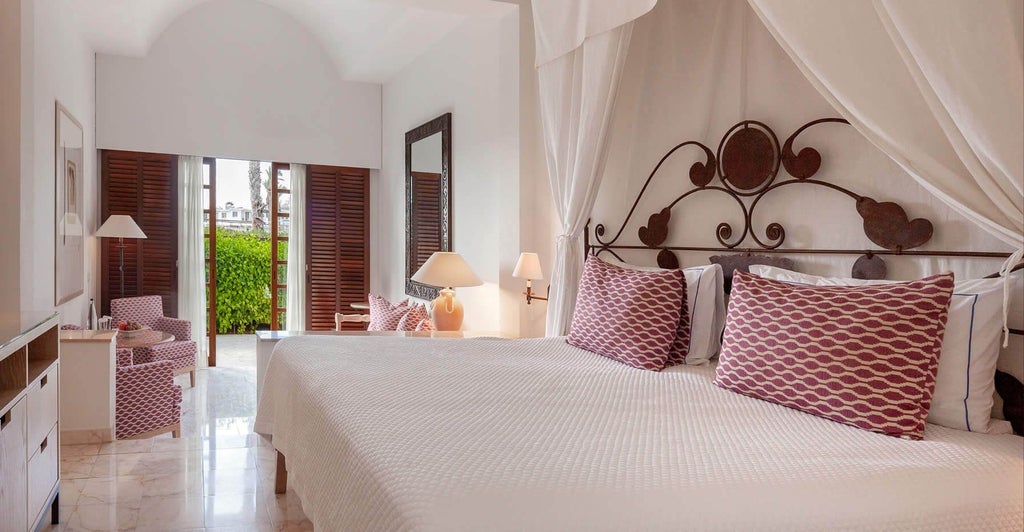 Spacious garden studio suite with modern furnishings, plush white bedding, sliding glass doors, and lush greenery at scenset Annabelle Hotel in Cyprus