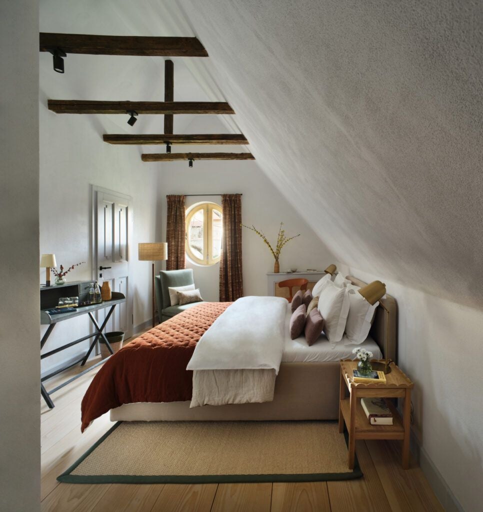 Rustic luxury corner barn suite at Bethlen Estates in Transylvania, featuring weathered wooden walls, elegant furnishings, and soft natural light streaming through large windows.