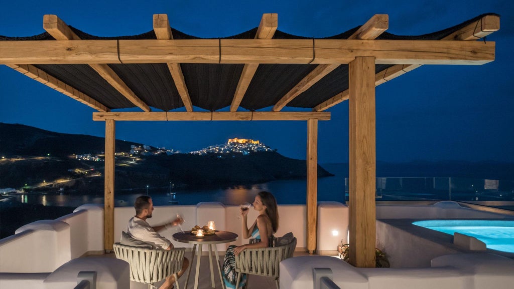 Luxurious white and blue Greek island suite with elegant balcony overlooking azure Aegean waters and traditional Cycladic architecture in Stampalia