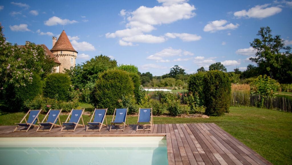 Tranquil French luxury estate with stone castle, verdant meadows, and serene pond reflecting historic architecture amid lush countryside landscape