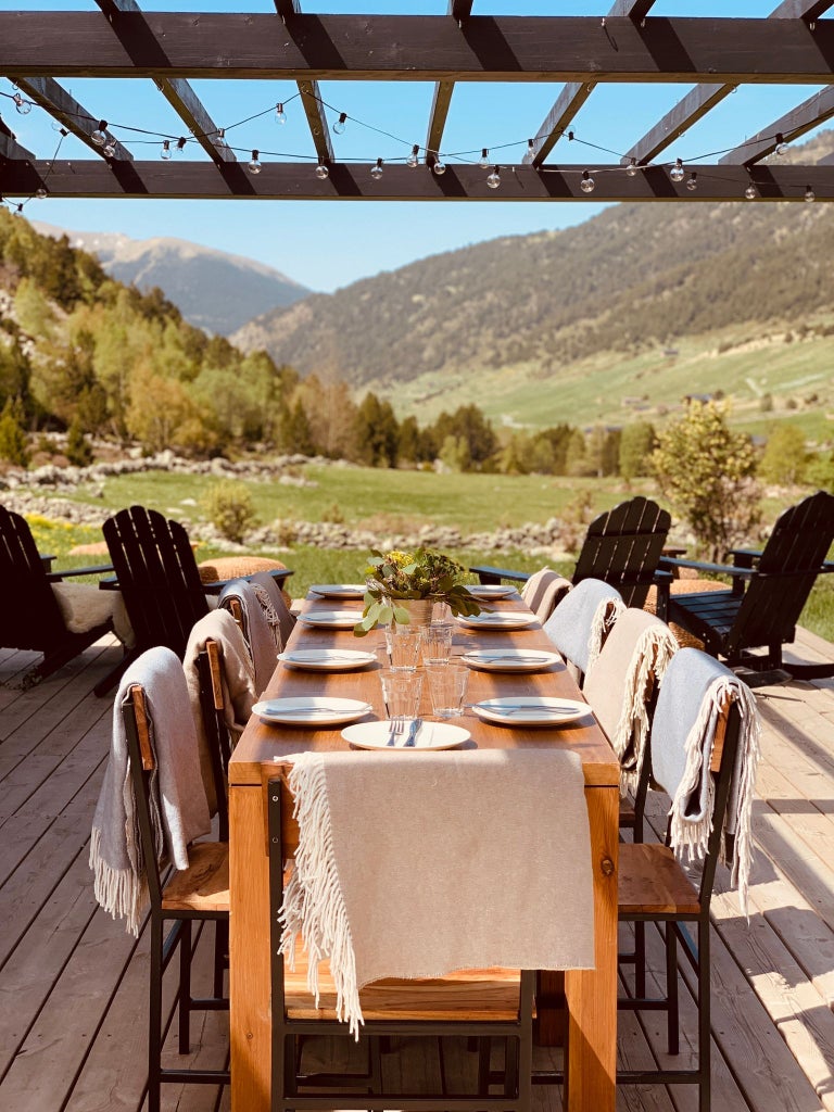 Luxurious mountain lodge nestled in Andorran peaks, with rustic wooden exterior, snow-capped mountains, and inviting warm lighting at dusk