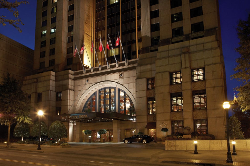 Elegant Four Seasons Atlanta hotel exterior with glass facade, marble columns, and ornate entrance beneath warm evening lighting