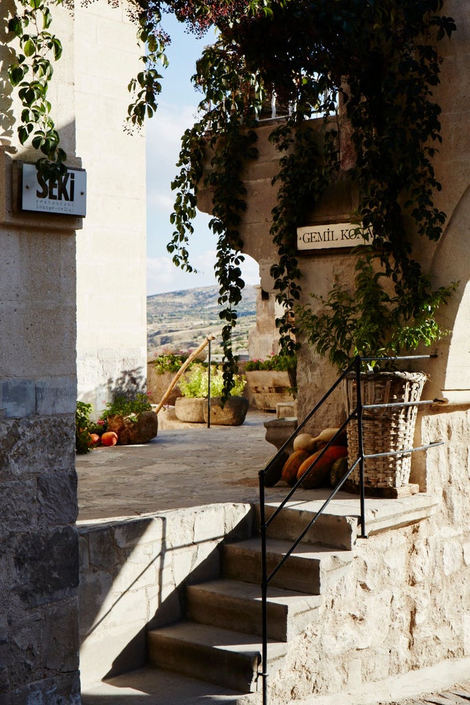 Luxurious stone-built hotel with arched windows nestled in Cappadocia's unique volcanic landscape, blending historic cave architecture with elegant design