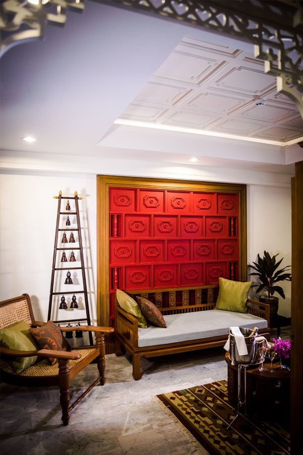 Large colonial suite with ornate wood furniture, four-poster bed draped in silk, crystal chandelier, and traditional Burmese design details