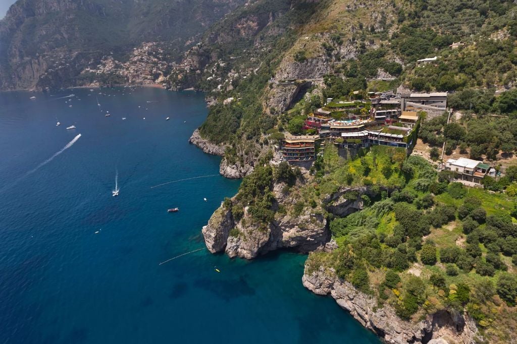 Elegant cliffside hotel in Positano with Mediterranean-style terraces, infinity pool overlooking the Amalfi Coast and azure sea.