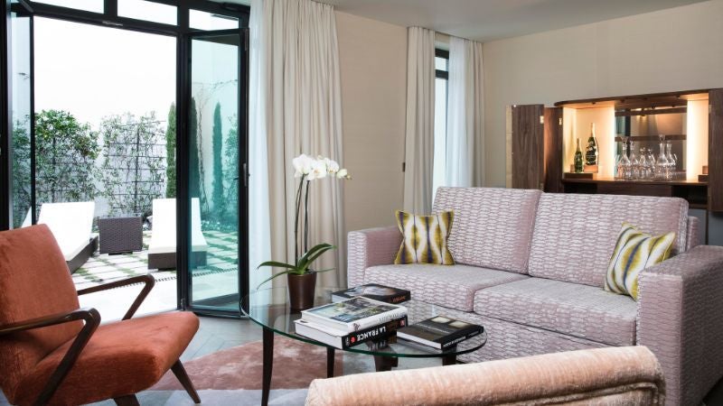 Elegant Parisian hotel interior with plush velvet seating, mid-century modern design, warm golden lighting, and sophisticated French architectural details