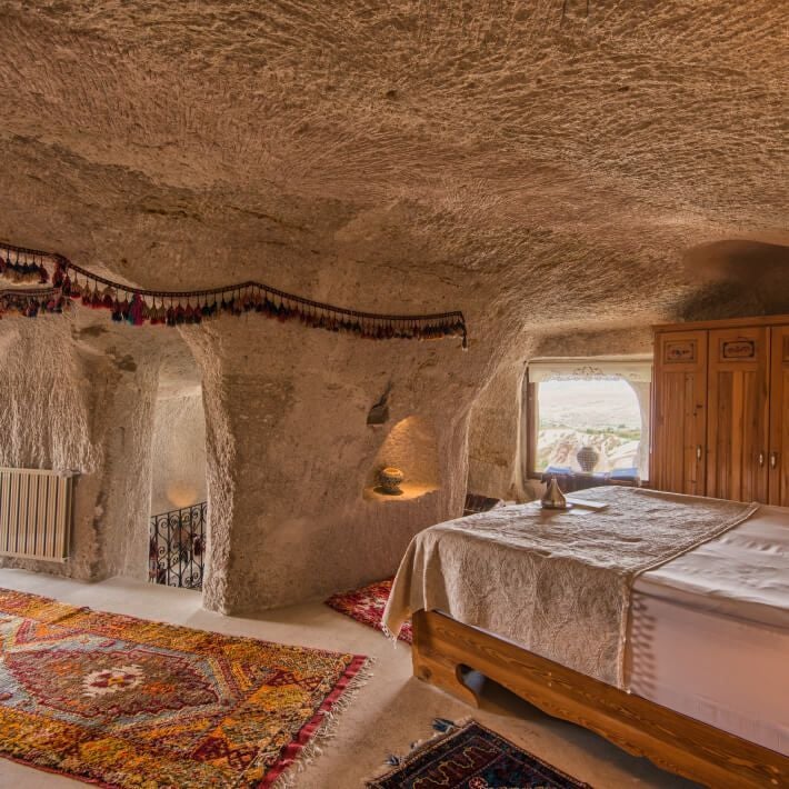 Luxurious deluxe suite at Museum Hotel in Turkey, featuring elegant stone walls, traditional Turkish decor, and plush bedding with city or landscape view