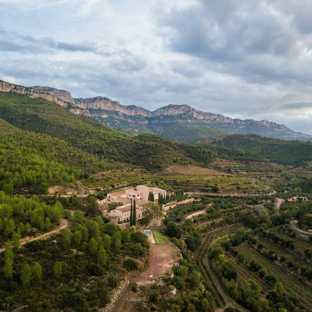 Luxurious stone-walled winery hotel nestled in scenic Spanish countryside, featuring rustic elegance with vineyard views and traditional architectural charm