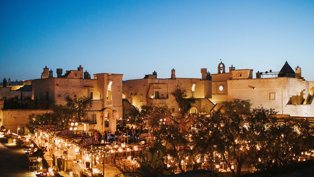 Elegant Italian luxury hotel with limestone facade, archways and Mediterranean gardens beneath a golden sunset sky