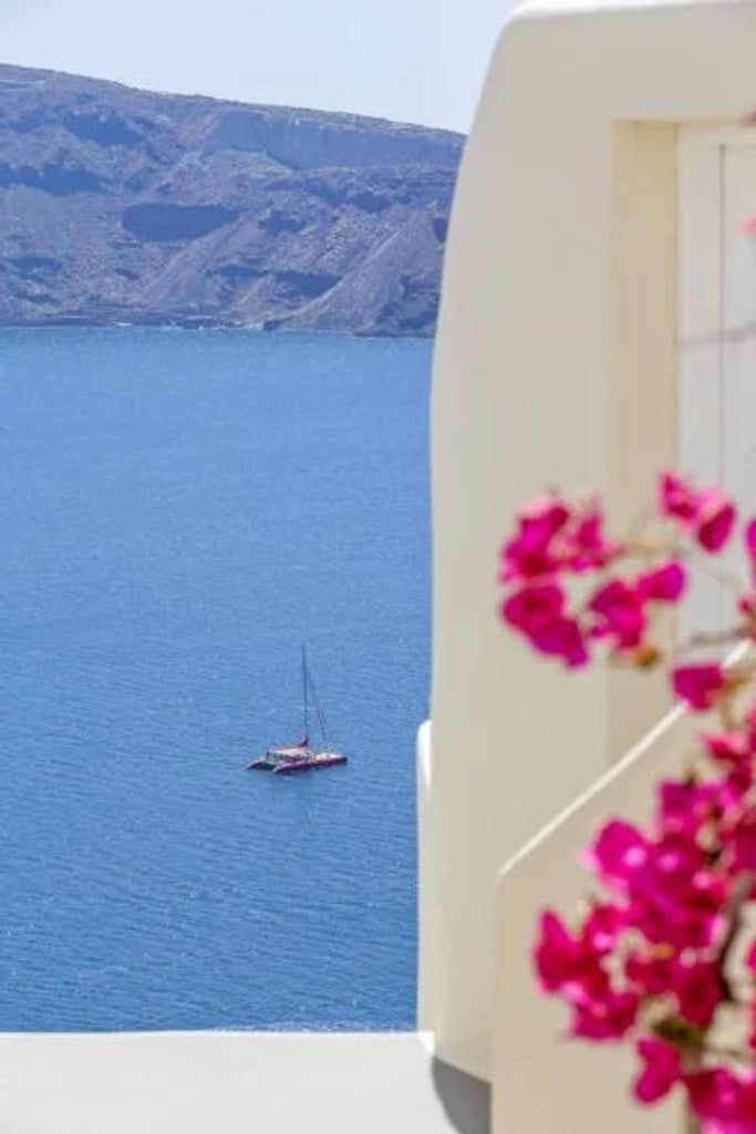 Luxurious white-washed suite with private infinity pool overlooking Santorini's caldera and Aegean Sea during golden sunset hour