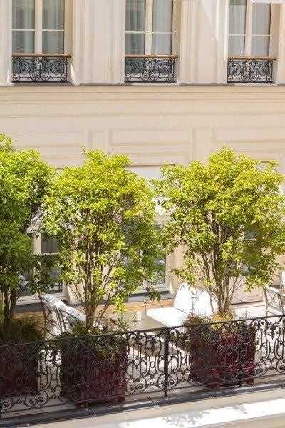 Elegant Parisian junior suite with private terrace, featuring plush white furnishings, soft natural light, and sophisticated contemporary design overlooking urban scenery