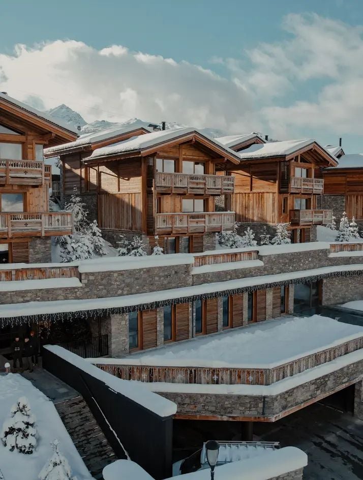 Luxurious alpine ski resort hotel nestled in snow-covered Courchevel, featuring elegant chalet-style architecture with modern glass windows and pristine mountain backdrop