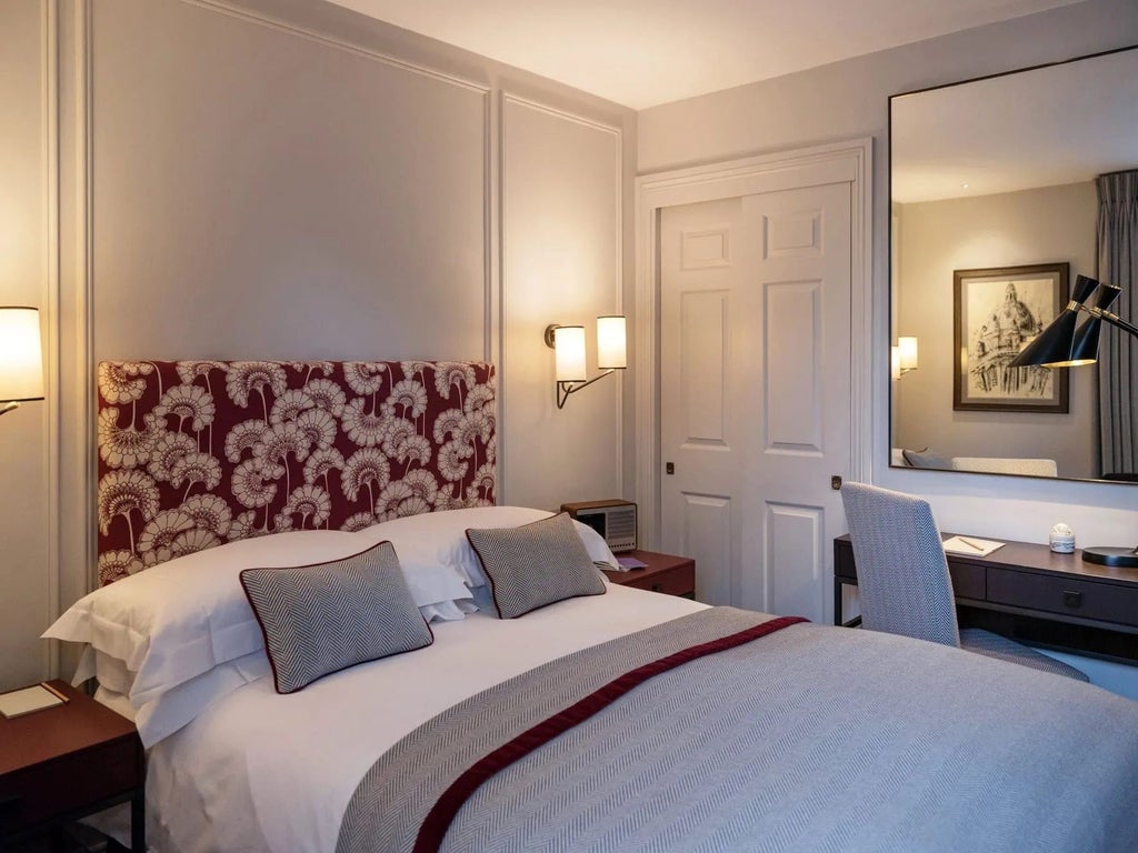 Elegant small double hotel room with classic wooden furnishings, plush white bedding, and vintage bank-inspired architectural details in a historic UK setting.