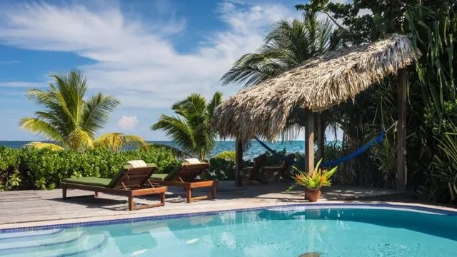 Elegant beachfront hotel room with wooden furnishings, white linens, and large windows overlooking lush tropical gardens in Argentina