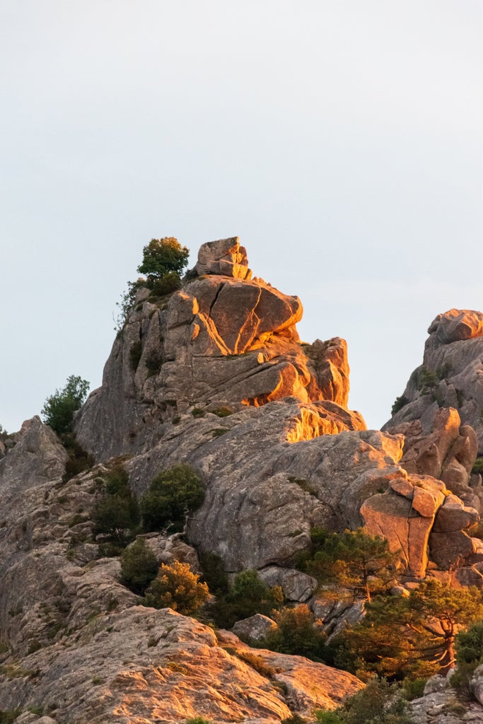 Panoramic view of turquoise Mediterranean waters meeting rugged cliffs of Corsica's coastline, with luxury yachts dotting the bay below