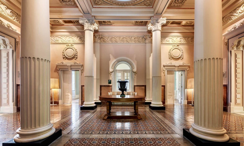 Elegant Vidago Palace Hotel's grand facade, showcasing white neoclassical architecture, lush gardens, and early 20th-century Portuguese luxury resort styling