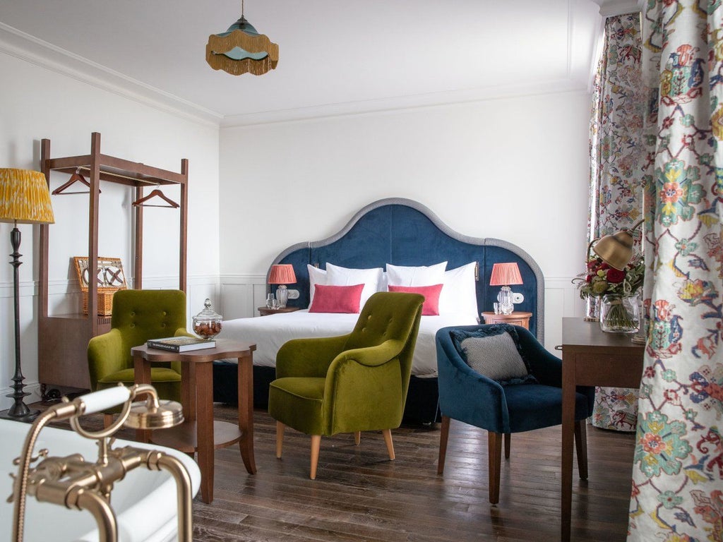 Elegant French luxury hotel room with soft neutral tones, plush bedding, vintage furnishings, and soft natural light streaming through refined windows