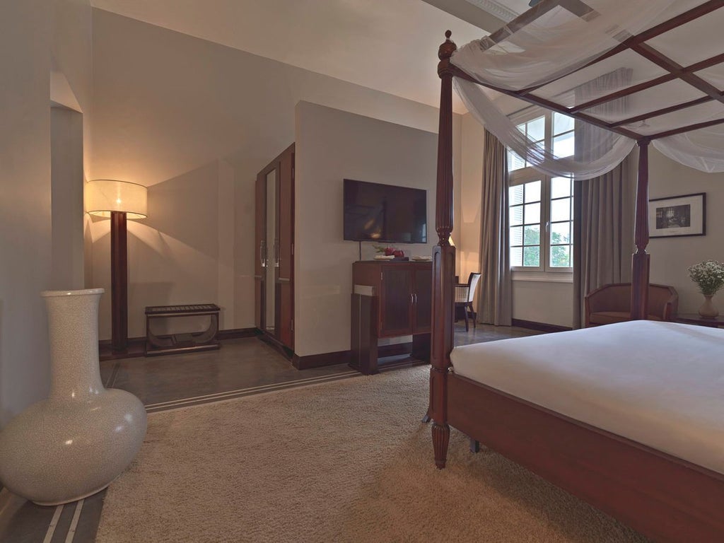 Elegant French colonial suite with antique wooden furnishings, white marble floors, and panoramic views of historic Hue cityscape through large windows