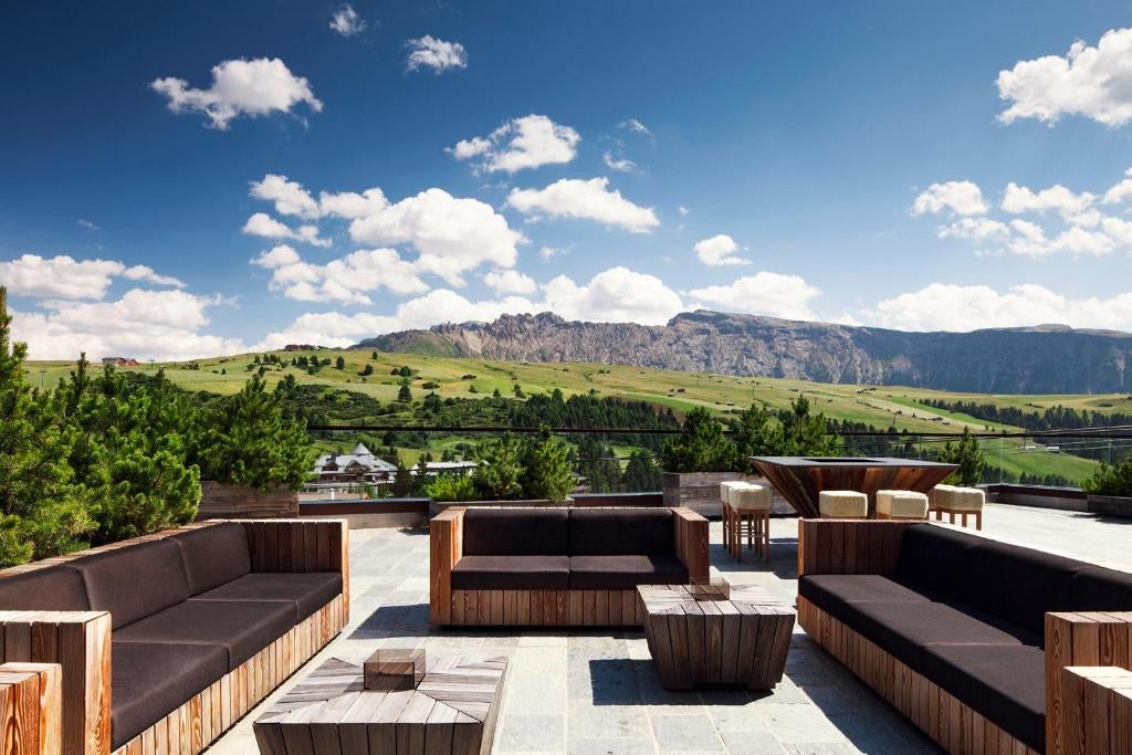 Modern mountain resort with glass facade nestled in snowy Italian Dolomites, featuring contemporary architecture and panoramic views