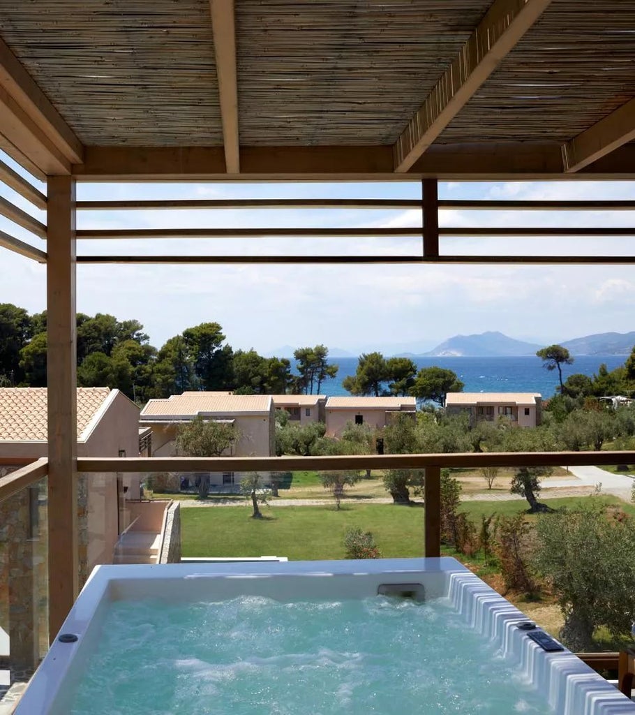 Luxurious interconnected suite at ELIVI Skiathos with private hot tub, modern design, and panoramic view of lush Greek island landscape