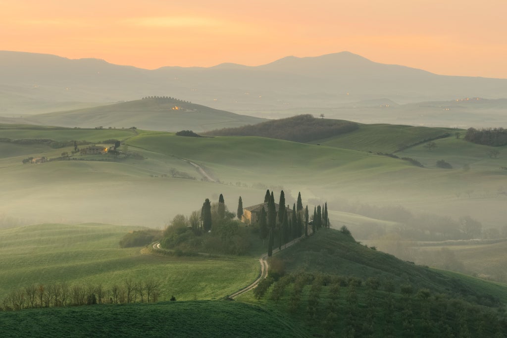 Historic stone towers rise above San Gimignano's medieval skyline, with rolling Tuscan hills and cypress trees stretching into the distance