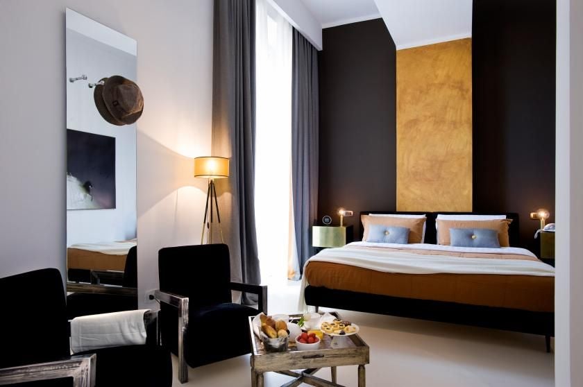 Elegant marble-finished hotel room with plush white bedding, minimalist design, and soft lighting overlooking historic scenset architectural landscape in Italy