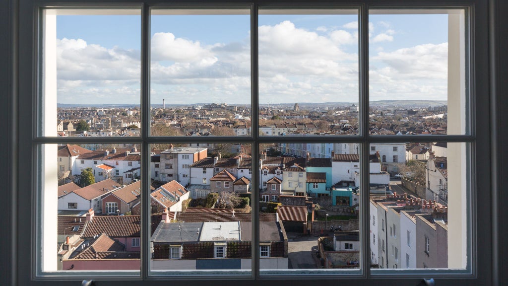 Spacious modern hotel suite with plush king bed, elegant workspace, large windows overlooking cityscape, sophisticated neutral color palette in United Kingdom accommodation