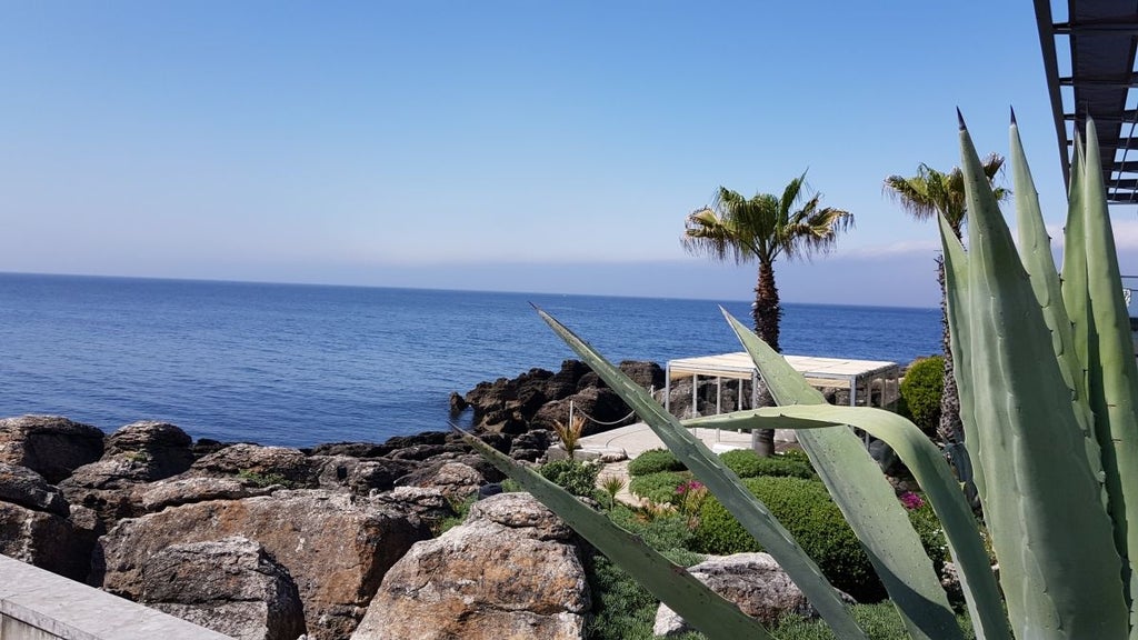 Luxurious coastal hotel with white facade, perched on rocky cliff overlooking azure Atlantic waters near scenic Portuguese shoreline