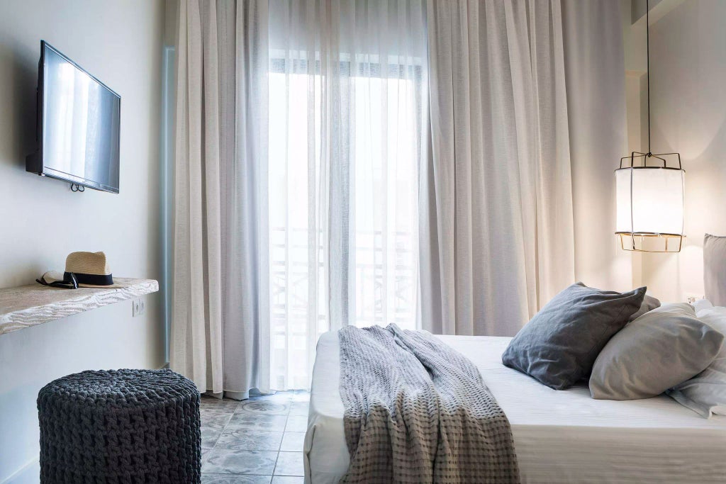 Elegant double room at Scenset Grand Hotel, featuring crisp white linens, modern decor, and panoramic side view of Greek coastal landscape through large window