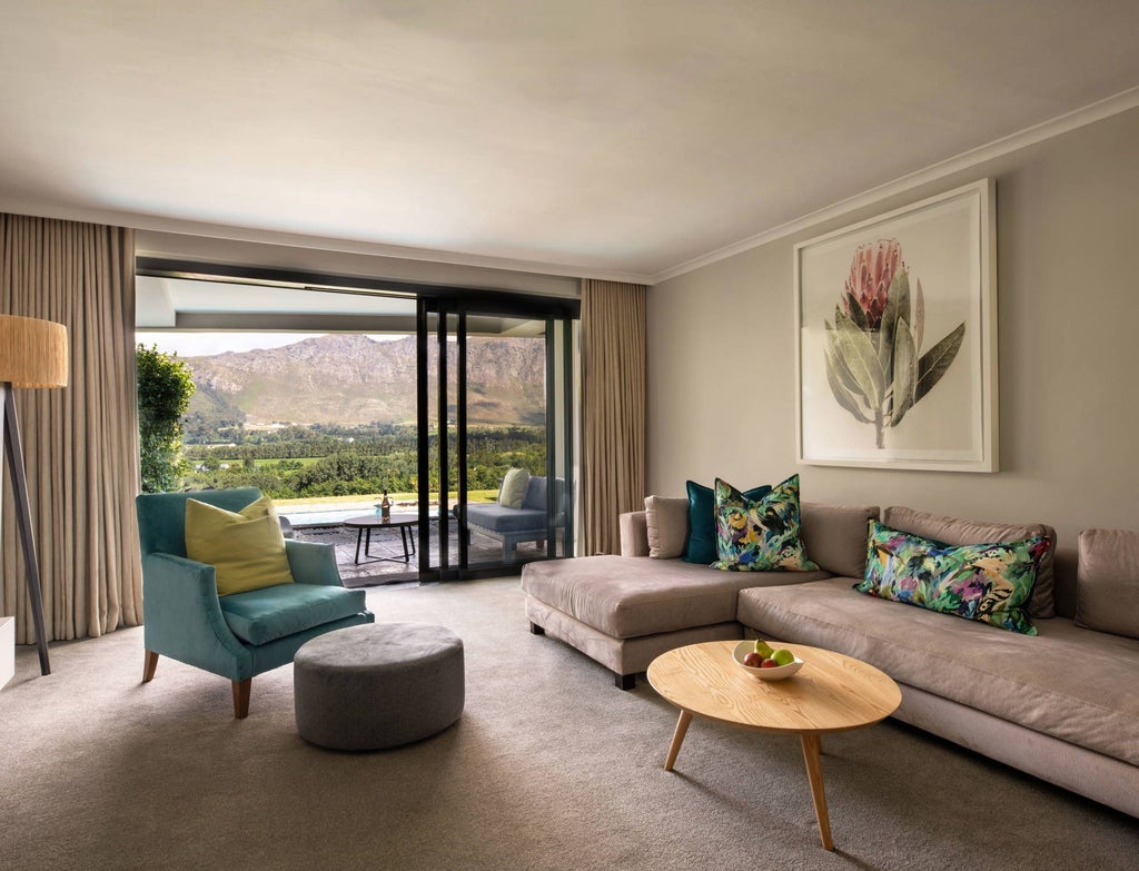 Luxurious Cape Winelands suite with elegant king bed, plush white linens, and expansive vineyard views through large modern windows.