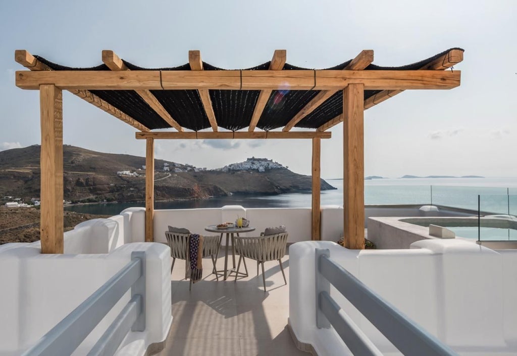 Elegant Greek honeymoon suite with white minimalist decor, plush king bed, private balcony overlooking Aegean Sea, and luxurious marble bathroom