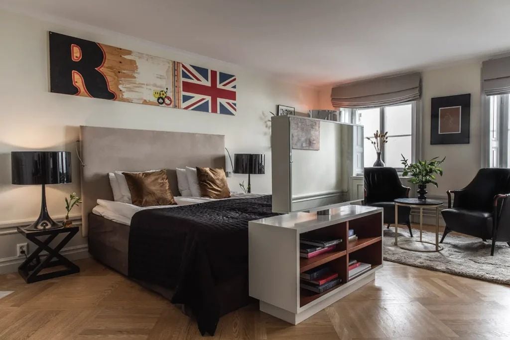 Elegant Deluxe Signature room at Scenset Hotel with plush king bed, contemporary Nordic design, warm wood tones, and city-view window in Stockholm