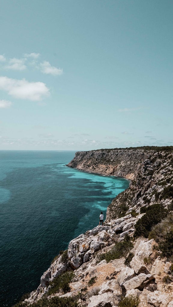 Aerial view of Formentera's pristine turquoise waters meeting white sandy beaches, with luxury yachts dotting the Mediterranean coastline