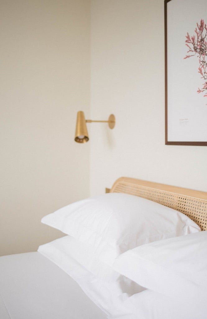 Elegant coastal-inspired hotel room with plush white bedding, soft blue accent wall, and nautical decor overlooking serene seaside landscape in UK boutique accommodation