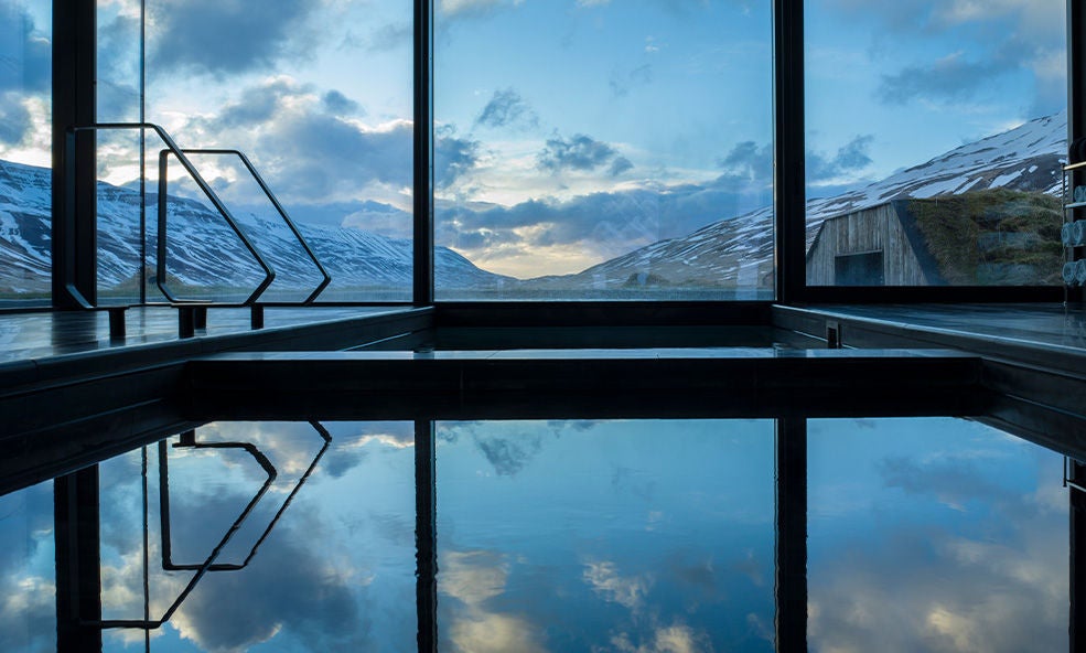 Serene geothermal spa with steaming turquoise waters, surrounded by rugged volcanic landscape and misty mountains in scenic Iceland.