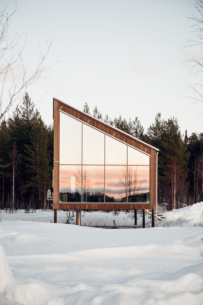 Rustic wooden family cabin room with minimalist Scandinavian design, large windows overlooking snowy landscape at Arctic Bath hotel in Sweden