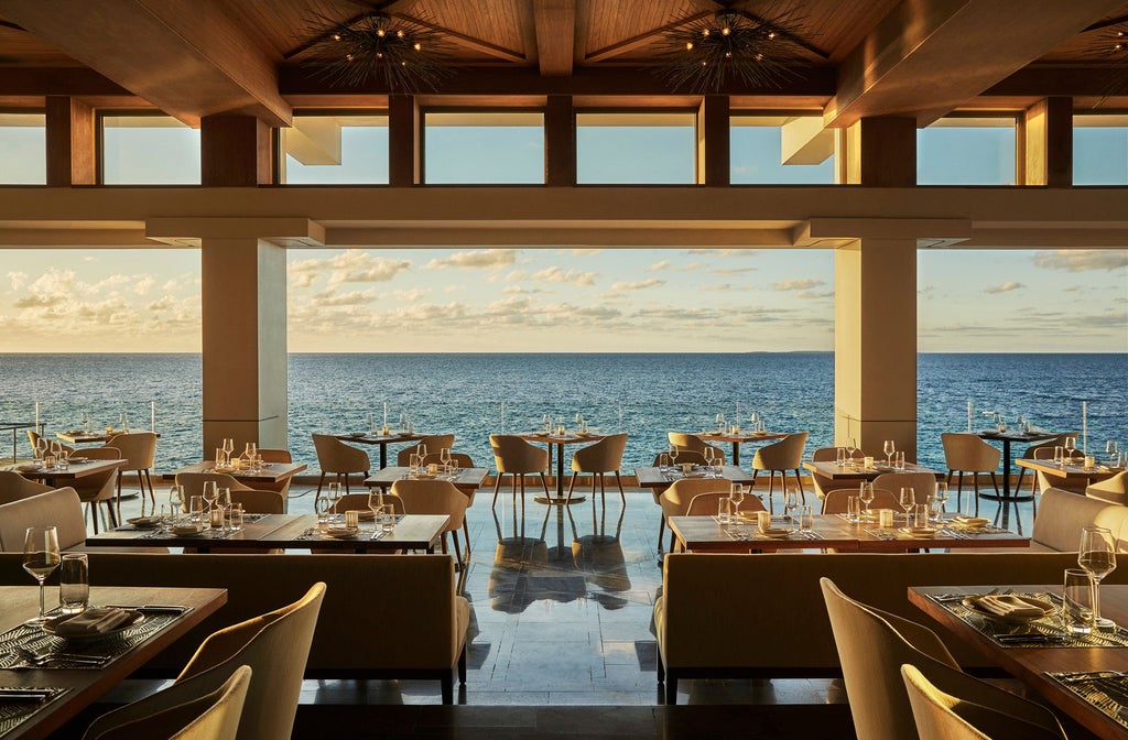 Beachfront infinity pool at sunset with ocean views, private cabanas and modern lounge chairs at Four Seasons Resort in Anguilla