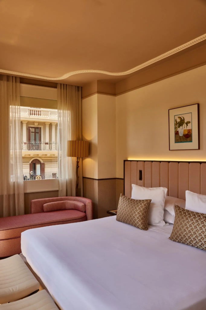 Luxurious deluxe corner hotel room at Grand Hotel Central, featuring elegant decor, panoramic windows with city and architectural views of Spain