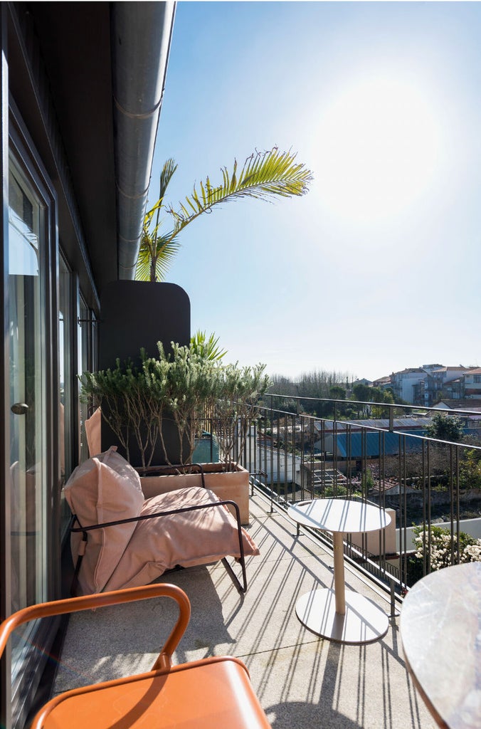 Elegant white boutique guesthouse with traditional Portuguese facade, wrought-iron balconies and climbing vines against blue sky