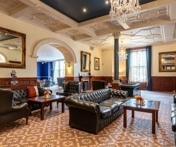 Elegant Victorian-era luxury hotel with grand stone facade, ornate windows, and manicured garden, showcasing timeless British architectural splendor in the United Kingdom.