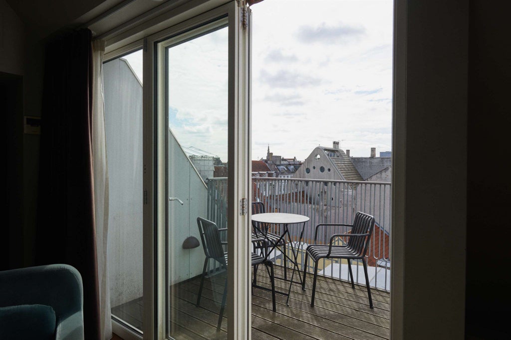 Elegant white historic hotel facade with classic Danish architecture, overlooking cobblestone street in central Copenhagen's scenic waterfront district