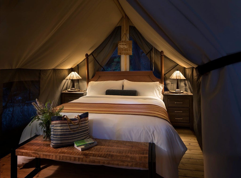 Luxurious safari-style tent nestled in Big Sur forest, featuring wooden deck, premium bedding and forest canopy views at dusk