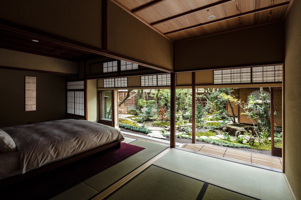 Traditional Japanese ryokan with modern luxury touches: elegant wood paneling, stone garden path, ambient lighting and minimalist design